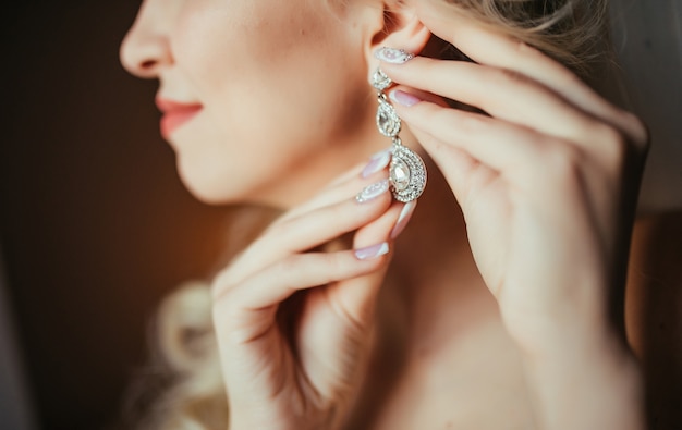 Woman wearing sparkling diamond drop earrings in an elegant close-up portrait.