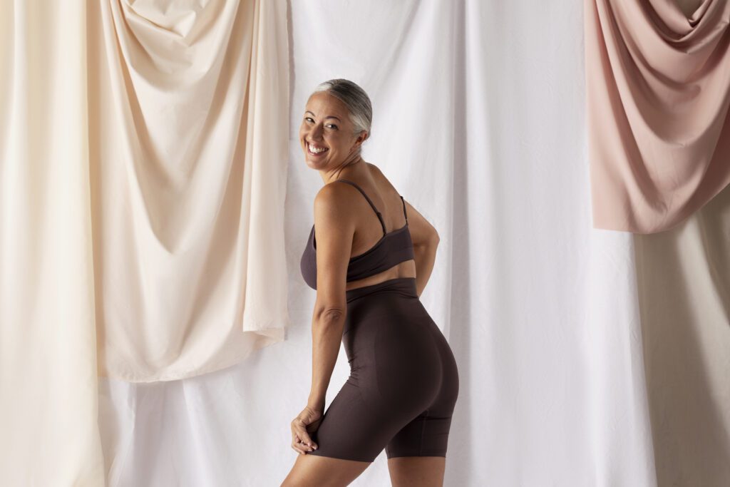 Woman posing in a studio, side view, showcasing her outfit and silhouette.
